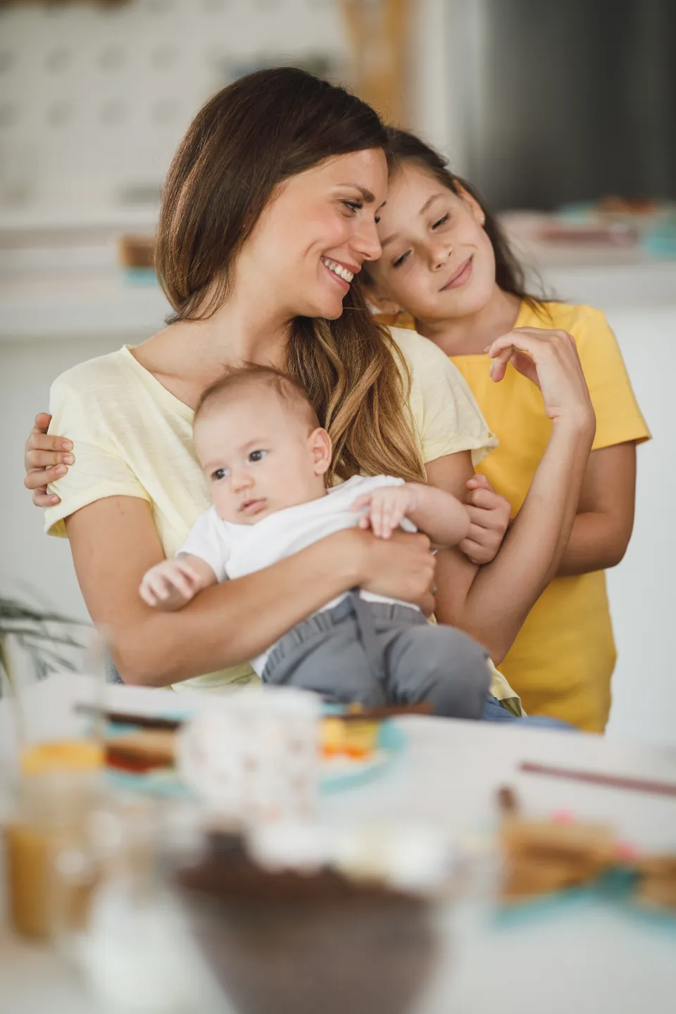 A mother holding her baby with her young daughter beside her
