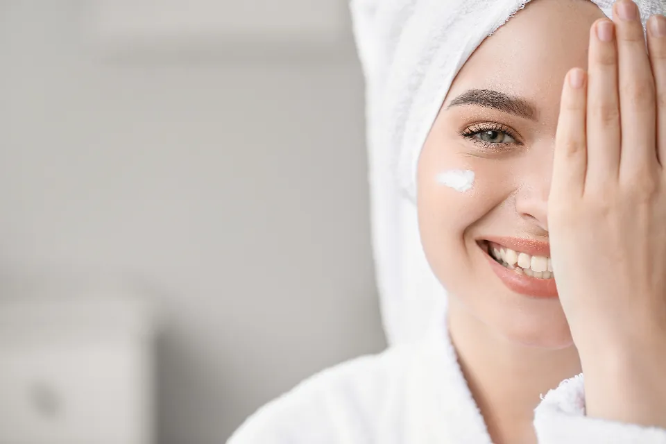 A smiling woman touches the skin on her cheek