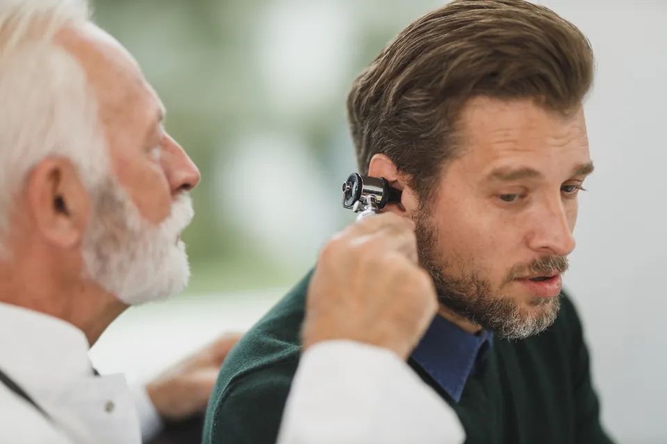 A doctor checks a patient's ear with an otoscope